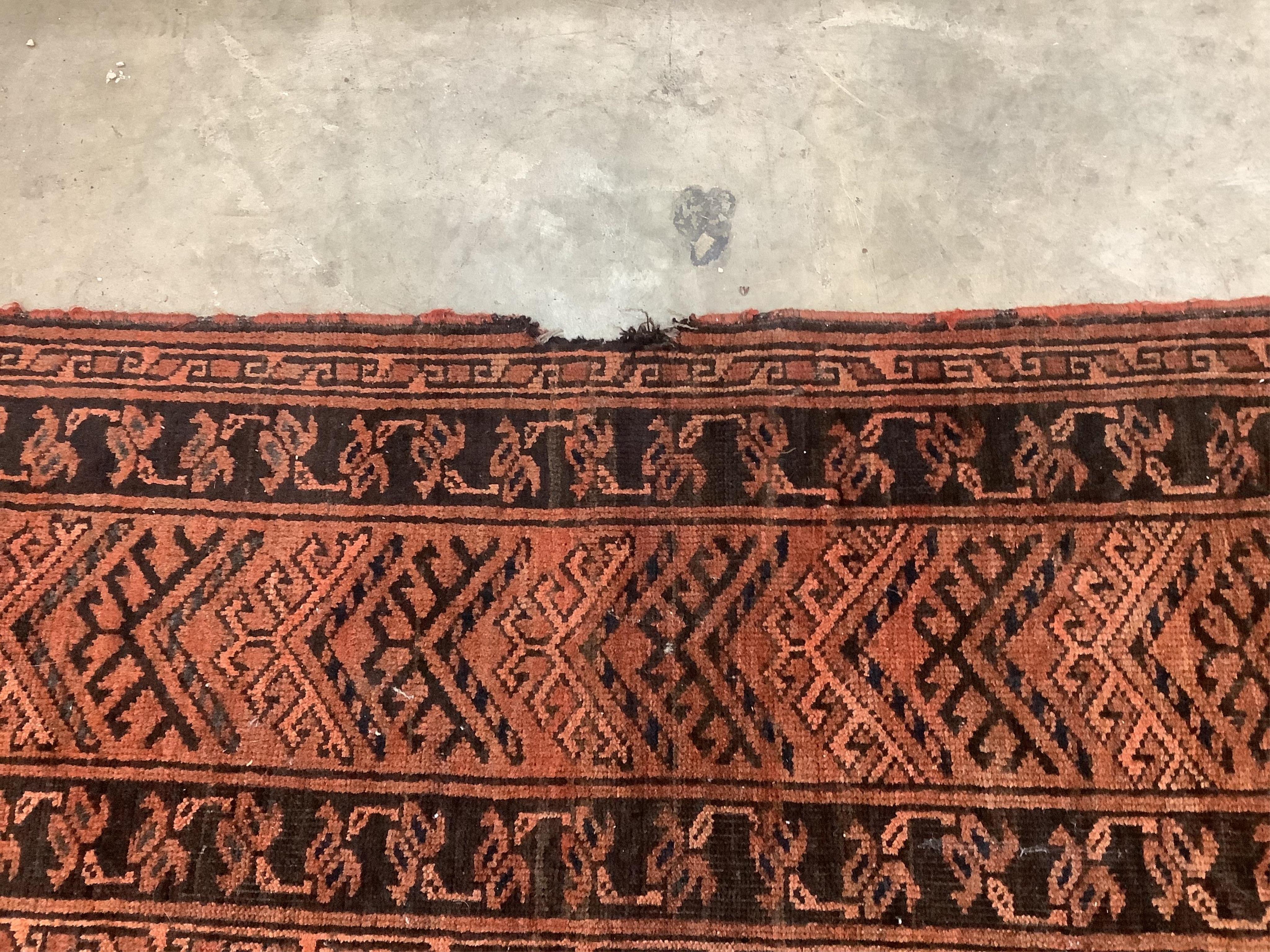 An Afghan rust ground carpet, 400 x 260cm. Condition - poor, damage to border